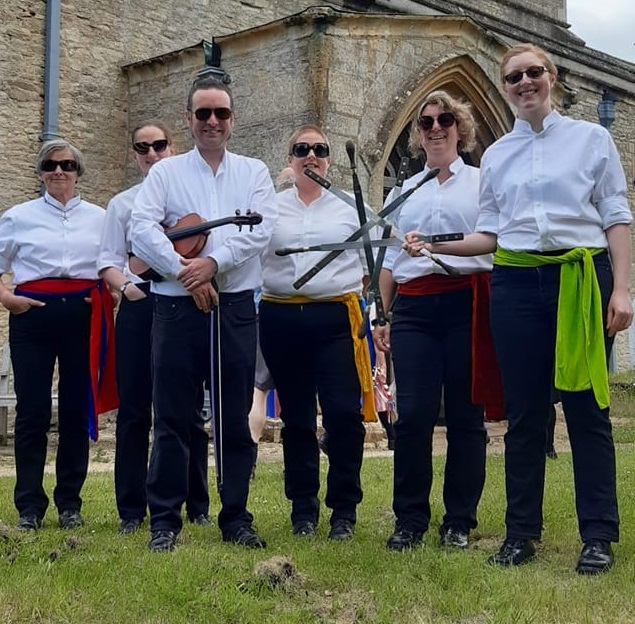 Moody Mabels, wearing shades, in front of Kirtlington church